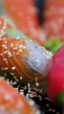 Koyu bir tabakta baharatlı sosla servis edilen taze otlar ve susam tohumlarıyla süslenmiş çıtır böreklerin genel manzarası. Bahar börekleri, hafif tuzlu kırmızı balıklar.