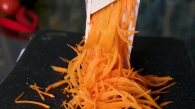 Bir kadın mutfakta havucu parçalamak için öğütücü kullanır. Bu geleneksel yöntem emek gerektiren bir yöntemdir ve modern mutfak aletlerine kıyasla sakatlanma riski taşır. Yüksek kalite 4k görüntü