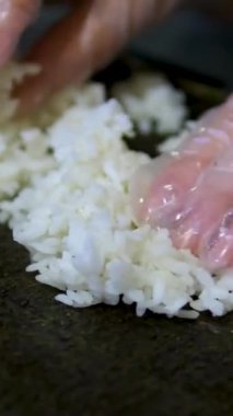 Suşi çekim yapıyor. Deniz yosunu. Siyah eldivenli şef deniz ürünleri suşisi hazırlar. Somon ve avokado ile suşi rulo. Lezzetli Japon yemekleri. 4 bin. Kapatın. Yüksek kalite 4k görüntü