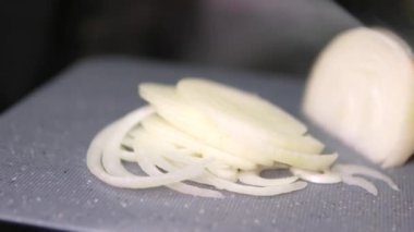 Ahşap bir kesme tahtasının üzerinde bir mutfak bıçağıyla çiğ soğan doğramak. Makro atış. Sağlıklı sebze yemeği pişirmek. Yüksek kalite 4k görüntü