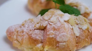 Bir kadın eli, badem yapraklarıyla kaplı bir kutu kruvasan açar. Pastanede tatlı, tatlı pasta. Yüksek kalite 4k görüntü