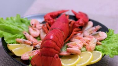 Büyük pişmiş kırmızı ıstakozu limonlu ezilmiş buzun üzerinde, yanında da limonlu. Taze, sulu ıstakoz kavramı masada tropikal meyve maaşlarıyla lüks bir şekilde sunuluyor. 