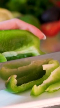 Ahşap kesim tahtasının üzerinde mutfak bıçağıyla el doğrama yeşil biber, yakın çekim. Yüksek kalite 4k görüntü