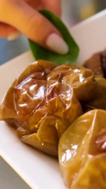 Elmalı kaz pişmiş ördek dolması, tepside doldurulmuş elma, ördek göğsü kesen kadın eli. Üst Manzara. Karamelli elmalı kaz ciğeri. Yüksek kalite 4k görüntü