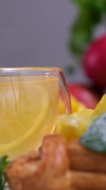 Kaşık egzotik bitkisel çay fincanına engel oluyor. Cam fincanda sarı çay ve nane üzümü.