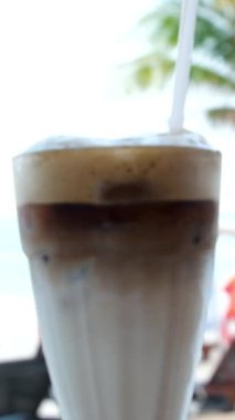 Kahve dükkanında pipetle bardakta buzlu latte kahve içmek. Soğuk yaz içeceği. Yüksek kaliteli FullHD görüntüler