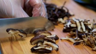 Şef şampiyon mantarlarını büyük bir bıçakla keser. Aşçı doğranmış mantarları büyük bir jöle kasesine koyar. Yer mantarlı makarna yapma süreci. Shiitake mantarı.