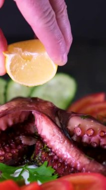 Yunan tavernası ahtapot restoranı yakın çekim servis ediyordu. Beyaz bir tabakta servis edilen kavrulmuş ahtapot dokunaçlarına taze limon suyu serpiyorum. Ahtapota limon suyu serp.