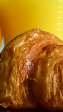 Şeffaf bardağa portakal suyu dökülüyor. Lezzetli kruvasanla süslenmiş. Çikolata ve gökkuşağı seramik tepsiyle ahşap masaya serpiştirilmiş. Yüksek kalite 4k görüntü