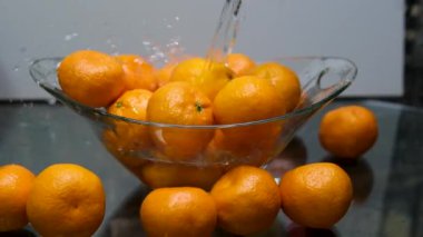 Yeşil yapraklı olgun mandalinalar cam bir kasede yıkanır. Yapraklı mandalinalar. Yüksek kalite 4k görüntü