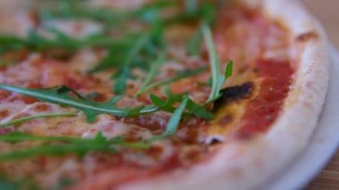 Kız bir dilim pizza alır ev yapımı pizza üzerine roka, domates dilimleri ve peynirle kaplanmış, pişirme malzemeleriyle çevrili. Yüksek kalite 4k görüntü