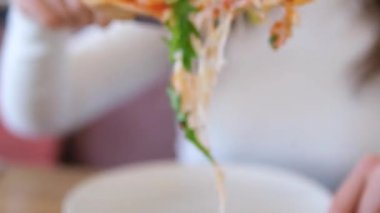 Kız bir dilim pizza alır ev yapımı pizza üzerine roka, domates dilimleri ve peynirle kaplanmış, pişirme malzemeleriyle çevrili. Yüksek kalite 4k görüntü