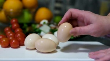 Kadın ellerinin yakın çekimi haşlanmış yumurtayı soyar. Deniz kabuğundan yumurta soymak. Akşam yemeği ya da haşlanmış yumurtalı salata. Yüksek kalite 4k görüntü