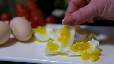 Yakın plan çekimde, haşlanmış bir Paskalya yumurtasından altın kabuğunu çıkarırken kabuğun parçaları tabağa saçılmış beyaz bir yama ortaya çıkıyor. Ağır çekim. Yüksek kalite 4k görüntü
