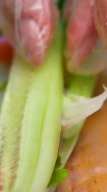 Suşi şefinin yan görüntüsü. Japon üçgenini pirinç kağıdına çeviren eller, yakın plan, taze sebzeler ve otlarla mutfak işyeri. Yüksek kalite 4k görüntü
