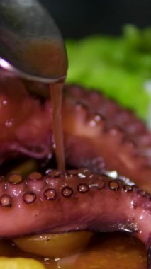 Sebzelerle servis edilen ahtapot, deniz ürünleri. Kaynamış ahtapot dokunaçları koyu taş bir tabakta, Asya, Akdeniz mutfağı, akşam yemeği. Üst Manzara. Siyah arka planda restoran menüsü. 4k 