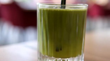 Kivi ve elmaların arasında yeşil buzlu içecek, dikey çekim. Portakal suyu ile kibrit çayı