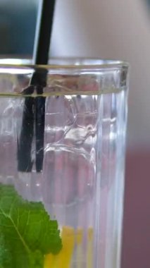 Taze yaz kokteyli yapıyorum. Buzlu bardağa karbonatlı su dökmek. Ağır çekim. limon ve limon dilimleri. Nane, ferahlatıcı soda tonik. Soğuk mojito limonata, köpüklü soda.