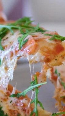 Kız bir dilim pizza alır ev yapımı pizza üzerine roka, domates dilimleri ve peynirle kaplanmış, pişirme malzemeleriyle çevrili. Yüksek kalite 4k görüntü
