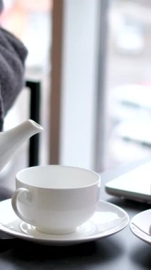 Sabahları televizyon kanalını değiştirirken sabahları bornoz giymiş bir fincan kahve ya da çay içen uykulu genç adam. Bornozlu bir adam banyodan sonra çay içer.