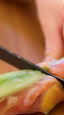 Suşi şefinin yan görüntüsü. Japon üçgenini pirinç kağıdına çeviren eller. Yakın plan, mutfak işyeri. Havuç, kırmızı balık biber ve salatalık sebzeli börek pişir.