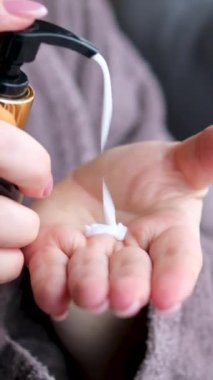 Cilt bakımı, hijyen ve sağlıklı yaşam konsepti. Kapatın. Banyoda yıkanmak, gelişmiş cilt bakımı için yumuşak jel kullanmak. Kadın elleri pompa plastik losyon şişesini itiyor ellerine nemlendirici krem sürüyor.