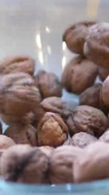 Kabuğu soyulmamış ceviz kabukları şeffaf bir cam kasenin içinde, ceviz çekirdekleri beyaz bir cam tabağın üzerinde ve metal bir fındık kıracağının üzerinde. Fındık faydalı bir üründür. Sağlıklı bir yaşam tarzı. Yüksek kalite