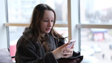 Güzel bir kadının internet uygulamasını iletişim için kullanması, koltukta oturması, mesaj yazması, konuşması, neşeli olması, gülümsemesi, yüzünü çevirmesi, düşünmesi. Yüksek kalite 4k