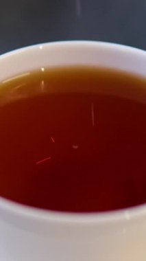 Siyah demlenmiş çay, metal bir çaydanlıktan beyaz bir fincana dökülür. Dolly etkisi. Kapatın. Ağır çekim. Çay takımı bulanık. Yüksek kalite 4k görüntü