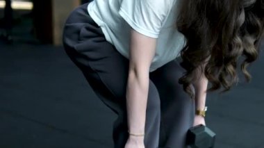 Spor haberleri. Egzersiz rutini. Yakın plan ağırlık kaldırma, odaklanmış kadın eğitimleri, modern bir spor salonunda antrenmanını tamamlamaya kararlı bir şekilde bir kettlebell 'e tutunmayı sıkılaştırıyor. Yüksek kalite 4k 