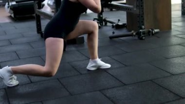 Spor eğitmeni ışık stüdyosunda dambıl çömelmesi yapıyor. Kasları iyi tanımlanmış güçlü bir kadın spor salonunda güç ve teknik gösterisi yapıyor. Harekete geçen motive bir kadın. 