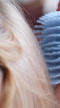 Saç ve kafa sağlığı için kafa derisine masaj yapmak için pembe silikon fırça kullanan bir elin yakın çekimi. Bornoz saunasında yetişkin bir kadın. baş fırçası masajı