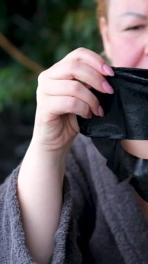 Bornoz saunasında yetişkin bir kadın. Siyah Yüzlü Maskeli Güzel. Maskeli kadın güzellik ve cilt bakımı. Tazelik ve saflık. Deri yenileme tedavisi. Gülümseyen kadın yüz masajı yapıyor.