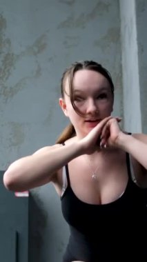 Beyaz spor ayakkabılı genç kız beden eğitimi dersinde adım adım kendini disipline sokma vücudunu şişirme hareketi yapıyor. Bir sınıftan birkaç video