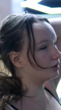 Aydınlık odada paspasın üzerinde genç fit spor egzersizleri. Evde spor ve spor eğitimi alıyorum. Sağlıklı bir yaşam tarzı. Uzanmak, öne eğilmek. Kız saçlarını açıyor.