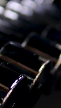 Spor salonunda ağırlık rafları ve arka planda görünen banklar gibi dayanıklılık eğitimi ekipmanlarıyla düzenli halterlerin sıra sıra odak çekimini yapın. Yüksek kalite 4k görüntü