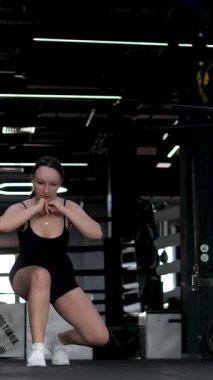 Beyaz spor ayakkabılı genç kız beden eğitimi dersinde adım adım kendini disipline sokma vücudunu şişirme hareketi yapıyor. Bir sınıftan birkaç video