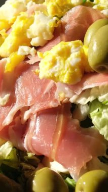 Mutfak masasındaki salataya zeytinyağı ekler. Genç bir kadın mozzarella salatası yapmak için çeşitli sebze ve peynirler kullanarak zeytinyağı döküyor. Yüksek kalite 4k görüntü