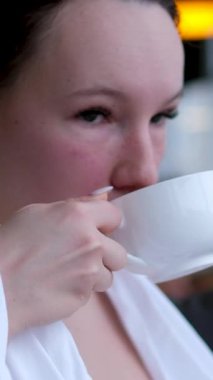 Kız çay içiyor ve spa bölgesinde yumuşak şezlongda dinleniyor. Ağır çekim. Yüksek kalite 4k görüntü