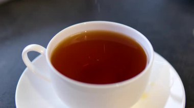 Siyah demlenmiş çay, metal bir çaydanlıktan beyaz bir fincana dökülür. Dolly etkisi. Kapatın. Ağır çekim. Çay takımı bulanık. Yüksek kalite 4k görüntü