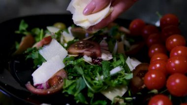 Peynir dilimleyen kadın ellerini kapat. Kadın şef peynir kesti. Ağır çekim. Peyniri ince dilimlere ayır. Kadın yemekleri. Bir malzeme hazırlıyorum. Yemek pişir. Salataya parmesan dilimi ekle