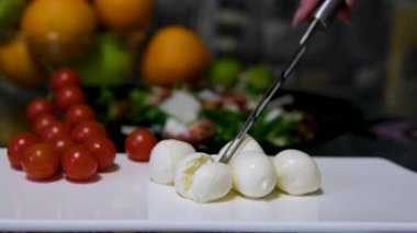 Kadın ahşap bir tahtanın üzerinde bir bıçakla mozzarella peyniri keser. Yüksek kalite 4k görüntü