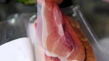 İnce dilimler halinde kurutulmuş prosciutto yakın plan, antipasto tabağı hazırlamak için incelik dilimleri. Yüksek kalite 4K görüntü. Yüksek kalite 4k görüntü