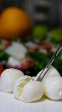 Kadın ahşap bir tahtanın üzerinde bir bıçakla mozzarella peyniri keser. Yüksek kalite 4k görüntü