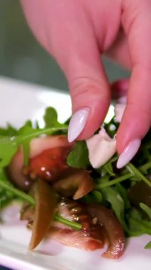 Restoran şefi pastırmayla süslenmiş sebze salatasına lezzetli, sert ve pahalı peynirler eklemek için maşa kullanır. Kapatın. Yüksek kalite 4k görüntü