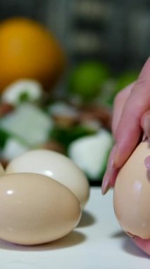 Eller ustalıkla kaynamış yumurtaların kabuklarını soyar ve pürüzsüz beyaz yüzeyi ortaya çıkarır. Yumurta kabukları tezgahın üzerine saçılır, aşçılık hazırlığı ve basitlik duygusu taşır. 4k