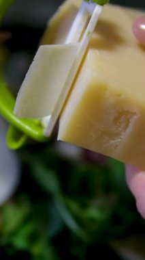 Peynir dilimleyen kadın ellerini kapat. Kadın şef peynir kesti. Ağır çekim. Peyniri ince dilimlere ayır. Kadın yemekleri. Bir malzeme hazırlıyorum. Yemek pişir. Salataya parmesan dilimi ekle