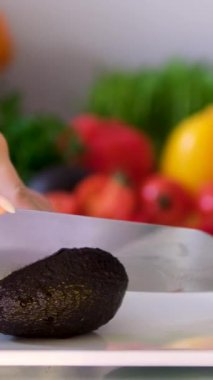 Avokado eti kepçeleyen erkek aşçı. Sağlıklı yemek hazırlamak, yarıya bölünmüş sulu avokado kaşıkla kepçelenmek, yakın çekim. Yüksek kalite 4k görüntü