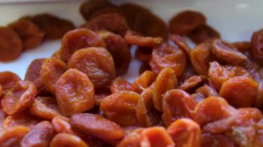 Sıcak ve davetkar bir mutfakta, kurutulmuş kayısılar ustalıkla hazırlanır ve sağlıklı bir atıştırmalık için servis edilir. Canlı, güneşin öptüğü meyve vitrinleri zengin altın bir renk, doğal tatlılığını vurguluyor.. 