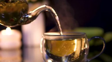 Mutfak masasında sıcak çay yapıyorum. Kaynar su çaydanlıktan bir çay poşeti ile bir fincana dökülür. Güneşli bir günde mutfak masasında şeffaf taze demlenmiş çay. Yüksek kalite 4k